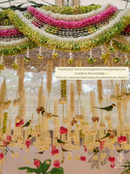 A close-up of the traditional floral arrangements we used to adorn the mandap. We handpicked auspicious elements like parrots crafted from leaves, jasmine, tuberoses, and chrysanthemums to create this intricate overhead decor.