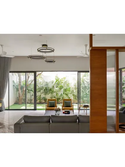This living room from our 'Solid Void Solid' house project exemplifies our principle of indoor-outdoor integration. Full-height sliding glass doors open directly onto a private garden, extending the living space and filling the interior with natural light and ventilation, creating a seamless connection to nature.