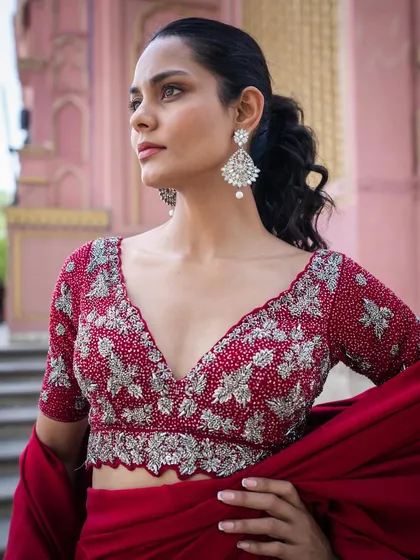 A close-up of the incredibly detailed, hand-embroidered blouse that comes with our rich red silk drape saree.