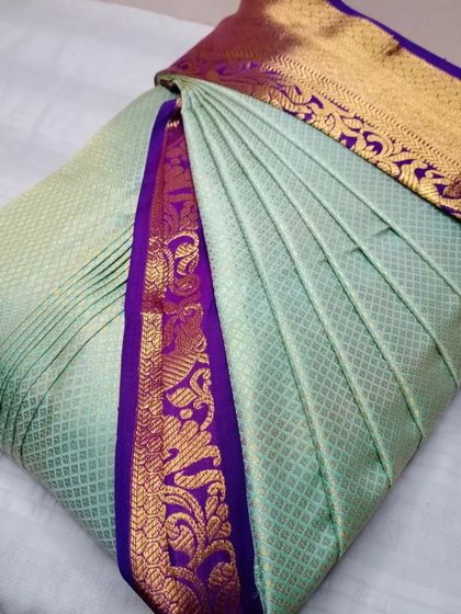 This pastel green saree with a purple and gold border is a great example of my work. The pleats are uniform and neat, ready for a flawless drape.