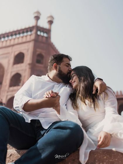 A tender moment of affection with the iconic Jama Masjid in the background, blending romance with the rich history of Old Delhi.