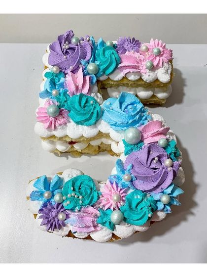 A number "5" monogram cake with strawberry filling. The colorful rosettes and pearl sprinkles make it a festive choice for a young child's birthday.
