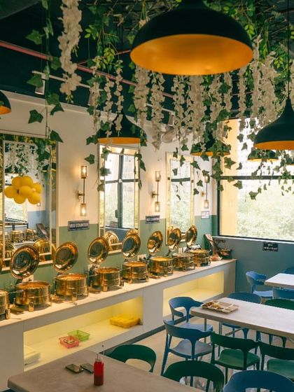 Another view of the dining area and buffet line at Spectrum Mall. The combination of mirrors and greenery makes the space feel bright and spacious.