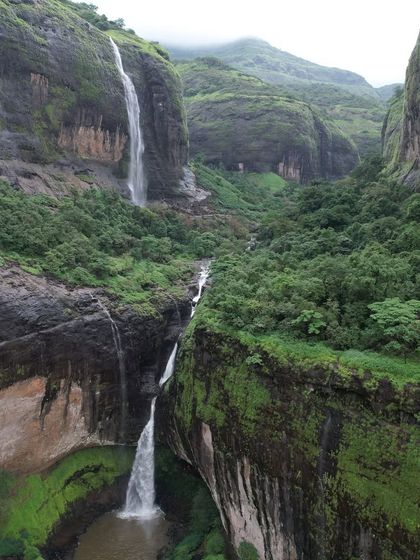 The breathtaking Devkund Waterfall, a plunge waterfall that creates a natural pool of clear blue-green water, hidden inside a dense forest.