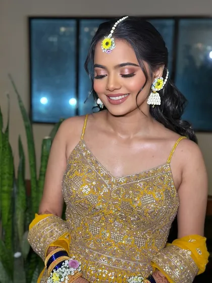 A beautiful smiling portrait of the Haldi bride. The makeup is kept soft and shimmery to complement the yellow outfit and floral accessories.