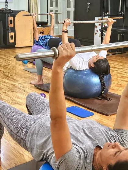 Building strength and balance on the ball. This exercise with the weighted bar challenges the core and upper body stabilizers.