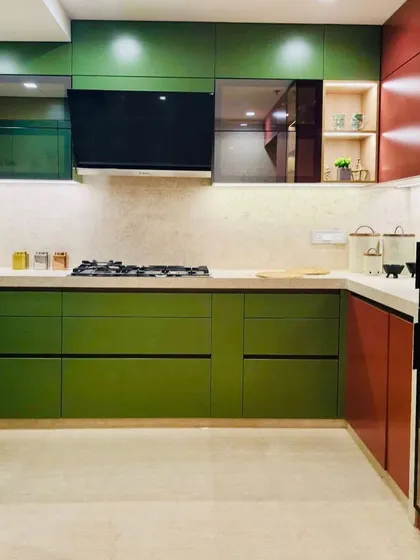 This kitchen makes a statement with its bold color blocking, using olive green and deep red cabinets. A tall, illuminated glass pantry adds a vertical element and display storage.