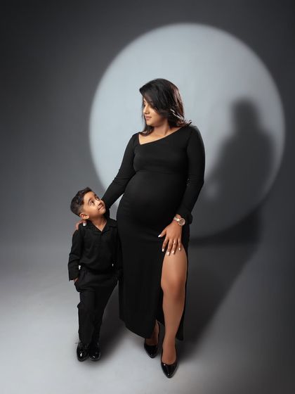 A powerful studio maternity portrait of a mother and her son. The dramatic spotlight on a simple grey background creates a classic and artistic image.