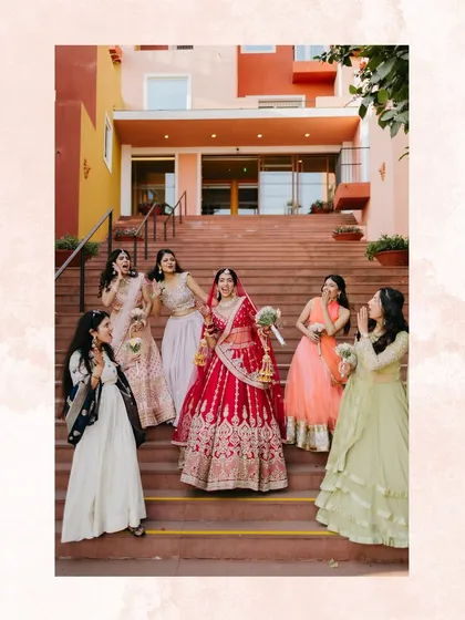The bride stands on a grand staircase surrounded by her excited bridesmaids, capturing their joyful reactions during her reveal.