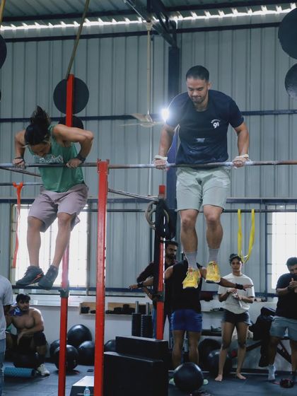 Competitors perform synchronized bar muscle-ups, a high-level gymnastics skill that requires immense strength and coordination.
