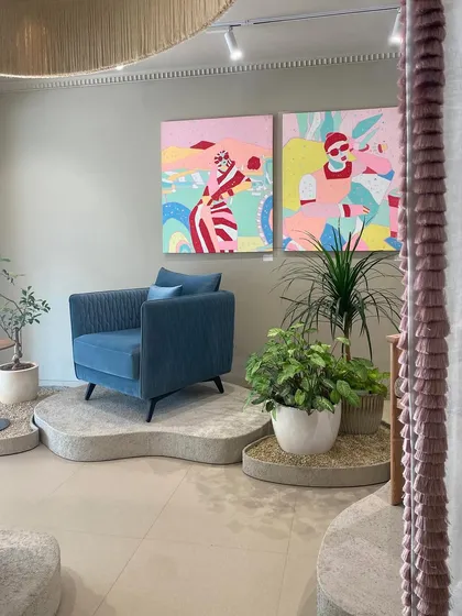 Vibrant art and bold furniture define this corner of the JOSMO store. A deep blue armchair sits on a custom terrazzo platform, creating a gallery-like setting that highlights the intersection of art and design.