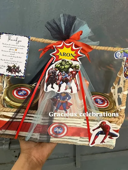 A super fun and budget-friendly superhero theme return favor for a 7th birthday. This jute basket is packed with themed decorations, jars of treats, and a gift for the kids.