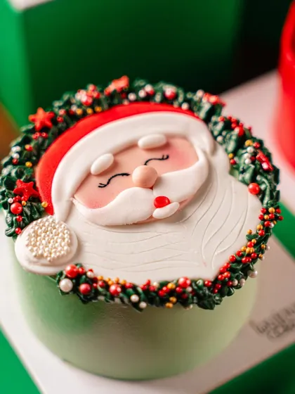 Our adorable Santa Mini Cake, featuring a cute fondant Santa face surrounded by a festive wreath. It's a delightful treat that is sure to bring a smile to anyone's face.