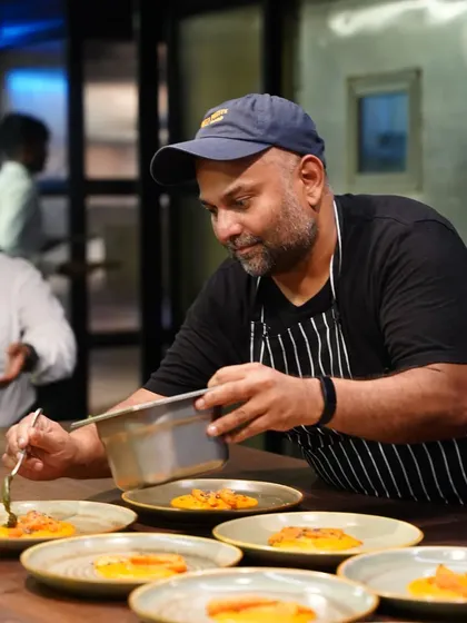 A chef in the middle of service, carefully plating multiple dishes with intense focus. This candid shot captures the high-energy environment and dedication of a professional kitchen.