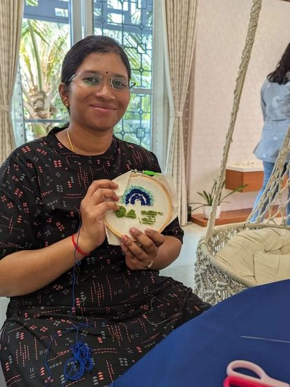 A proud crafter with her finished rainbow design, ready to be turned into a wall hanging or coaster.