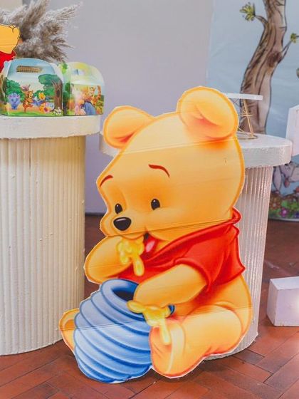 A close-up of a large Winnie the Pooh prop holding his honey pot, next to a light-up number '1'.