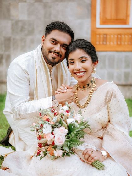 A sweet portrait of the couple seated in a garden, holding hands and sharing a happy moment with their beautiful bouquet.