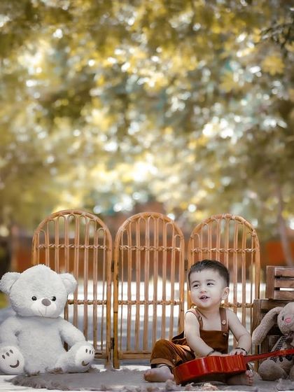 This little musician is ready to celebrate his first birthday. The outdoor setting is filled with rustic props like a mini guitar and wooden crates.