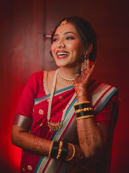 A candid shot of the bride's infectious laughter. Her joyful expression and traditional red saree create a vibrant and heartwarming portrait from her engagement ceremony.