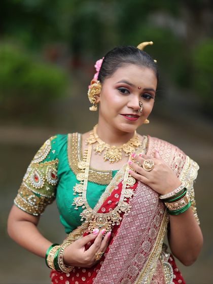 The complete look featuring a red dotted Nauvari, a heavily embroidered green blouse, and layered gold jewellery, perfect for a wedding ceremony.