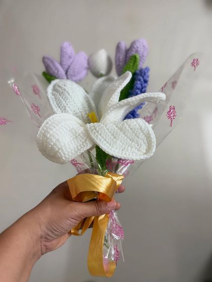 Holding the lily bouquet gives a sense of its size and how it would look as a gift. The clear wrapping and gold ribbon add a finishing touch.