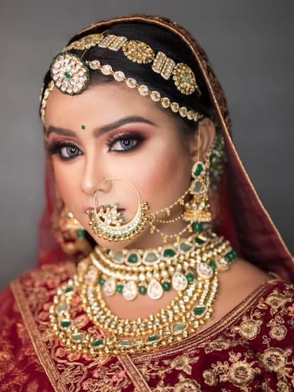 This bride chose a grand, traditional look with a heavy Kundan and emerald set, featuring a large nath and matha patti for a classic royal aesthetic.