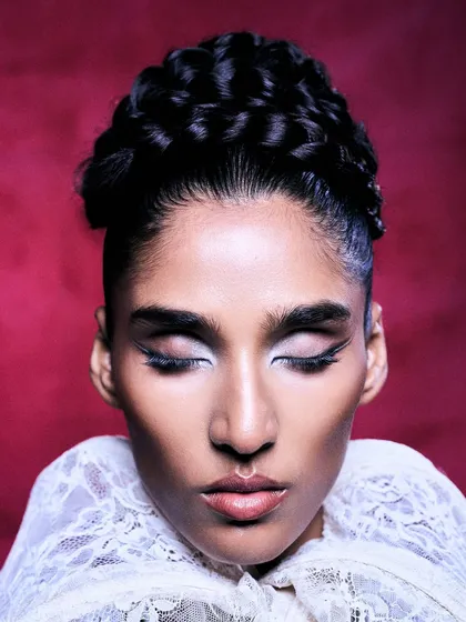A beauty editorial in Flanelle Magazine. The lighting is focused on the intricate braided hair and the dramatic winged eyeliner, creating a serene yet powerful portrait.
