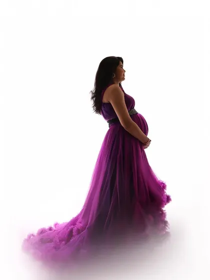 A beautiful silhouette against a white background. The rich purple and pink tones of the ruffled tulle create a cloud of color, making for an artistic and striking maternity portrait.