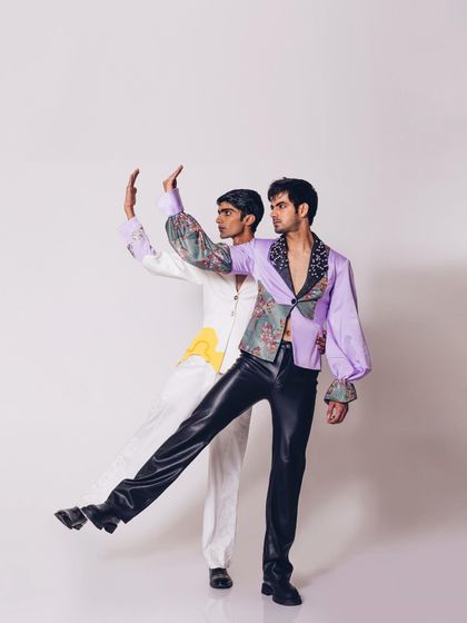 An editorial shot for Siddhant Agrawal's "Monsieur" collection, featuring two models in coordinated yet contrasting looks. The styling plays with color, print, and silhouette to create a dynamic and artistic composition.