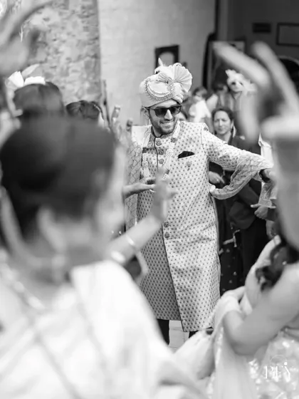 A black and white candid of the groom dancing with his friends and family during the baraat.