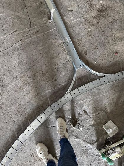 A metal framework for a curved design element being laid out on the factory floor. This shows the behind-the-scenes fabrication process that happens before installation on site.