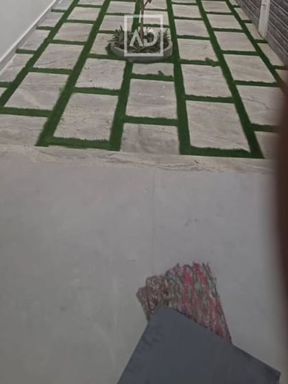 A long walkway using the stone and artificial grass pattern, leading to a central planter. This design adds visual interest to a simple path.