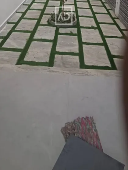 A long walkway using the stone and artificial grass pattern, leading to a central planter. This design adds visual interest to a simple path.