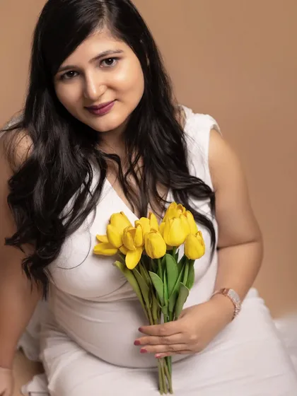 A soft and intimate close-up portrait. Holding a bouquet of yellow tulips, this mother-to-be radiates warmth and joy, showing how simple props can add a personal touch to your photos.