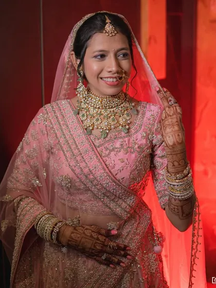 The red lighting adds a dramatic flair to this bride's soft pink bridal look, showcasing how the makeup holds up in different lighting.