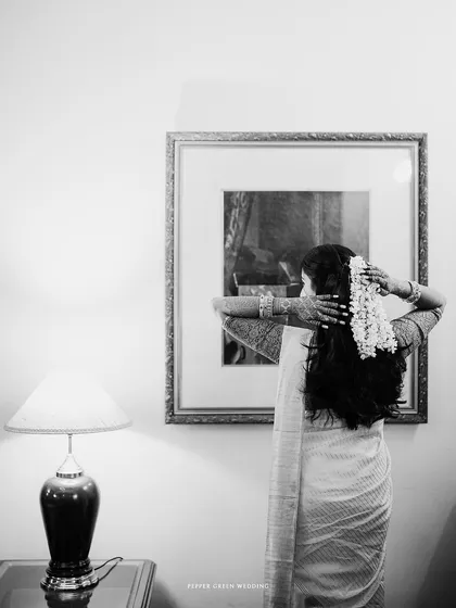 A serene black and white shot of the bride getting ready, a moment of quiet anticipation.