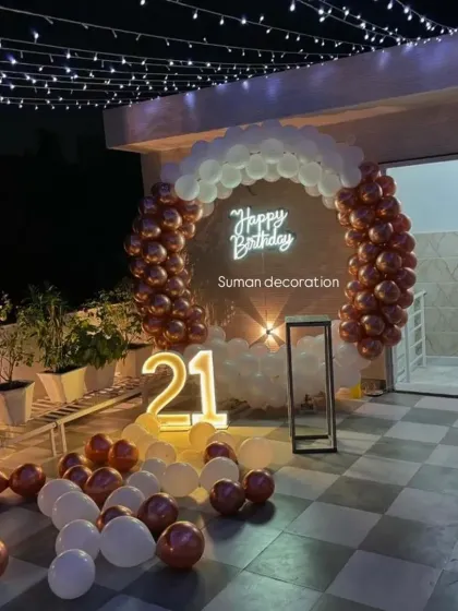 A chic 21st birthday party setup on a rooftop terrace. I used a circular balloon arch with rose gold and white balloons, a neon sign, and a light-up number to create a festive night-time vibe.