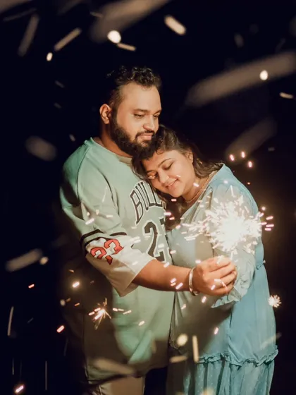 An intimate night shot of a couple holding a sparkler, with the warm light illuminating their faces. This is a perfect example of how we use props to create magical and romantic pre-wedding photos.