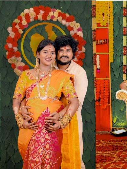 A happy, posed portrait of the couple at their baby shower. Their bright smiles and coordinated outfits reflect the joyous atmosphere of the celebration.