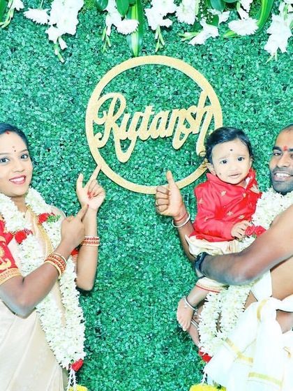 The proud family posing with the newly revealed name, "Rutansh," displayed as a golden cutout on the greenery wall.