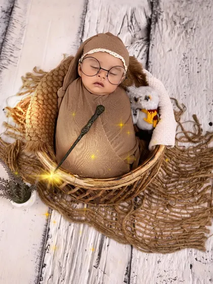 Another take on our magical Harry Potter theme. This newborn is swaddled and sleeping in a basket, complete with a wand and an owl, with a touch of digital magic for extra sparkle.