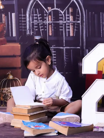 A two-year-old "bookworm" in our library-themed setup, looking intently at a book. A unique and creative way to celebrate a birthday.