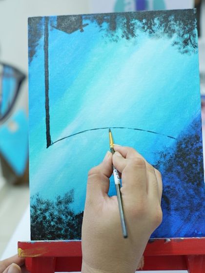 A close-up of a participant painting a night sky. The fine details, like the stars and trees, bring the scene to life.