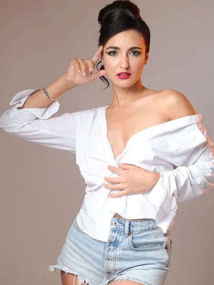 A classic fashion portrait of a model in a white shirt and denim shorts, exuding confidence and style.