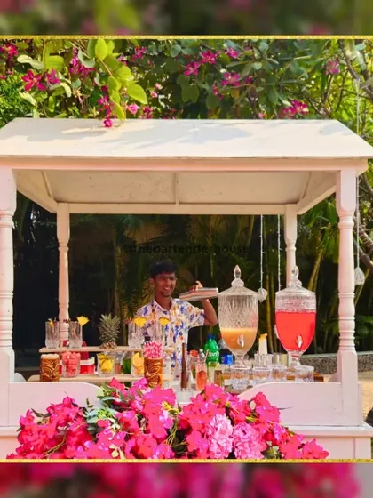 An enchanting and cute outdoor bar setup, perfect for a daytime garden party. The white cart is adorned with fresh flowers and dispensers for juices and punches.