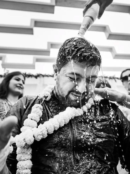 The groom getting a taste of the Haldi madness. This black and white photo captures the action and fun as Viraj gets drenched by his loved ones.