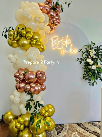 A closer look at our chic bridal shower decor, highlighting the "Bride to be" neon sign and the detailed balloon artistry. The combination of chrome gold, rose gold, and cream balloons with sprigs of greenery creates a refined and stylish look.