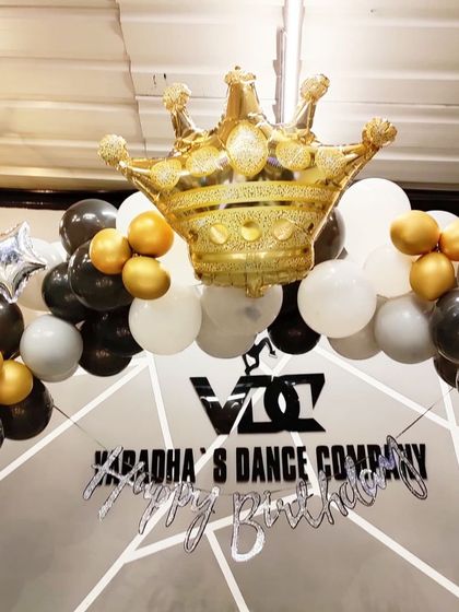 A close-up of the balloon arrangement for a stylish birthday party. The large gold crown foil balloon serves as a perfect topper for the black, white, and gold balloon garland.
