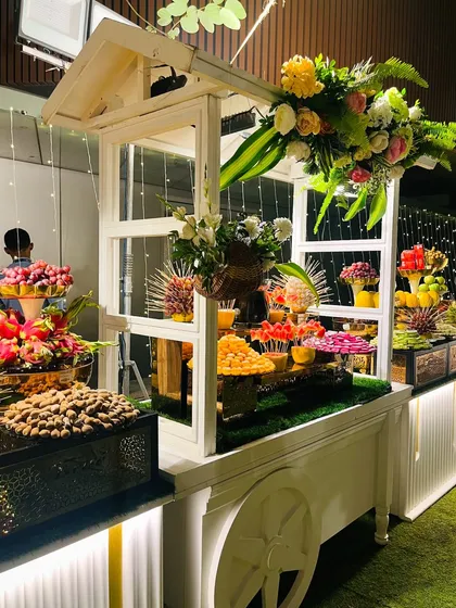 This charming white cart serves as a fruit and dessert station, complete with a chocolate fountain and fresh flower arrangements.