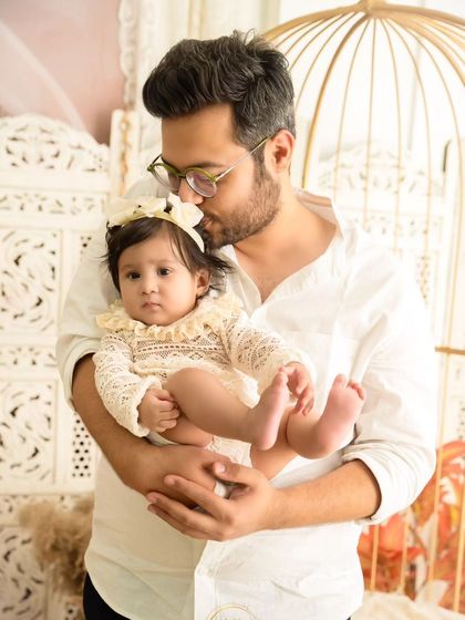 A tender moment between a father and his baby daughter, as he gently kisses her forehead.